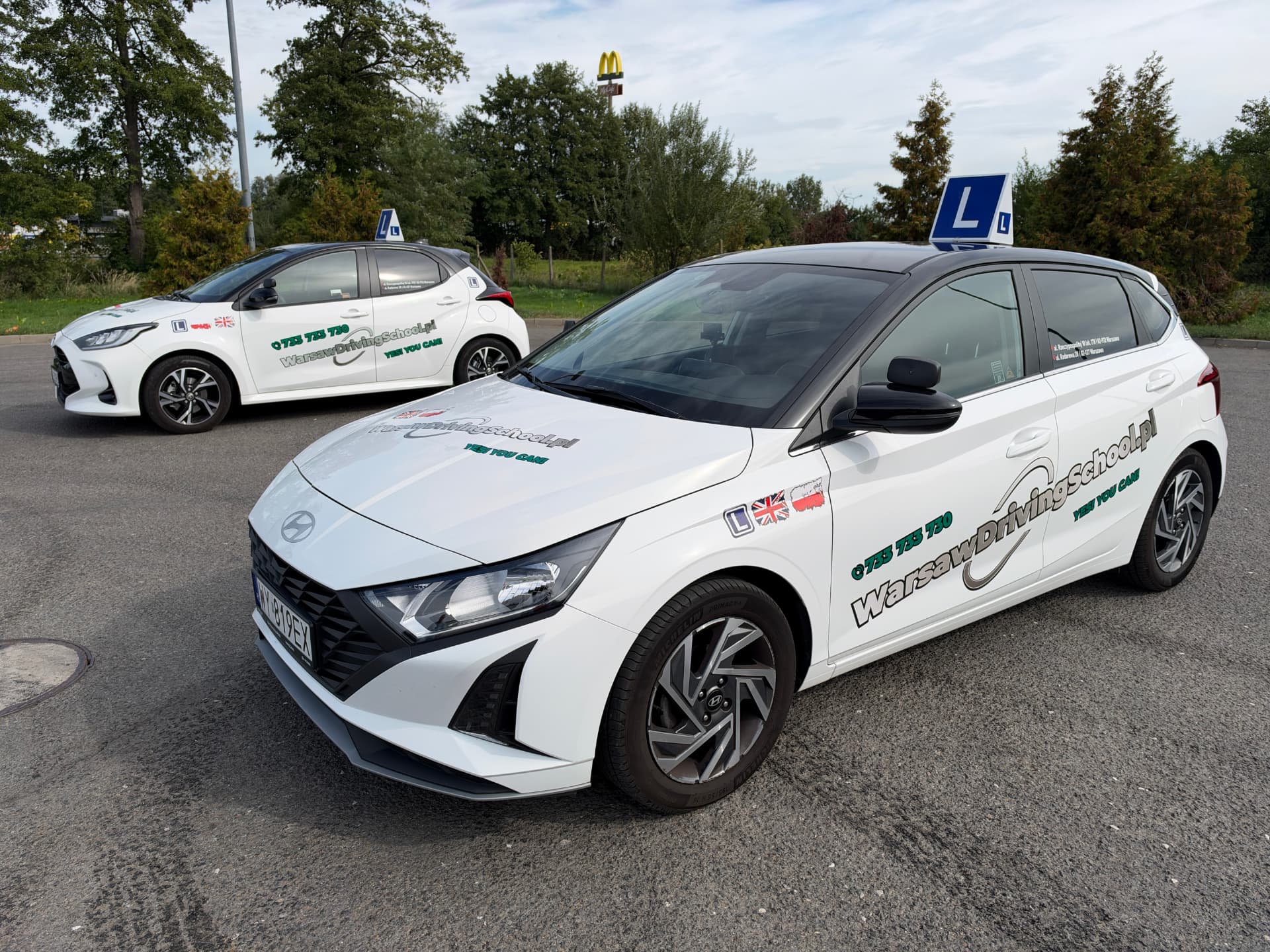 Hyundai i20 i Toyota Yaris Warsaw Driving School z tabliczką L na placu manewrowym